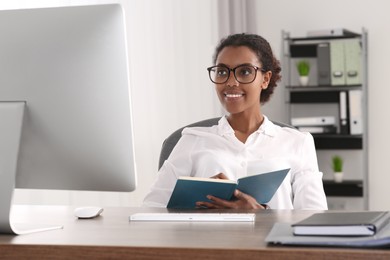 Photo of African American intern working with computer at table in office