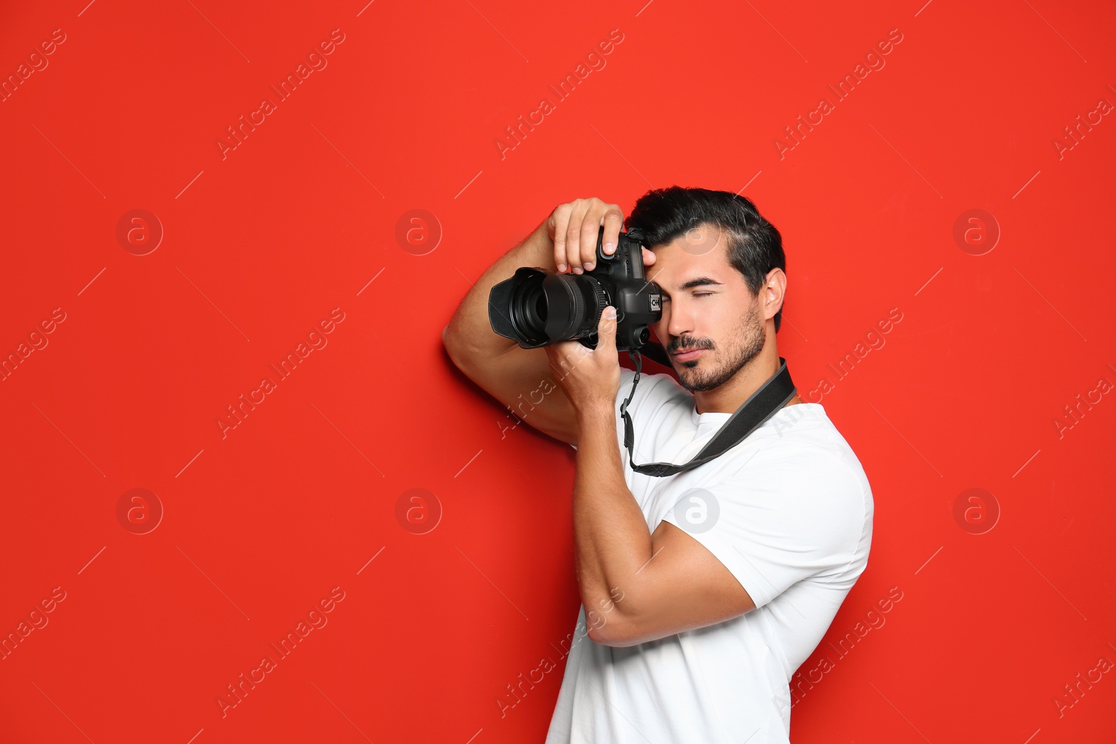 Photo of Young professional photographer taking picture on red background. Space for text