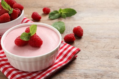 Photo of Delicious raspberry mousse with mint on wooden table, space for text