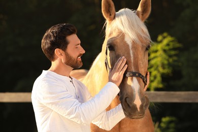 Handsome man with adorable horse outdoors. Lovely domesticated pet