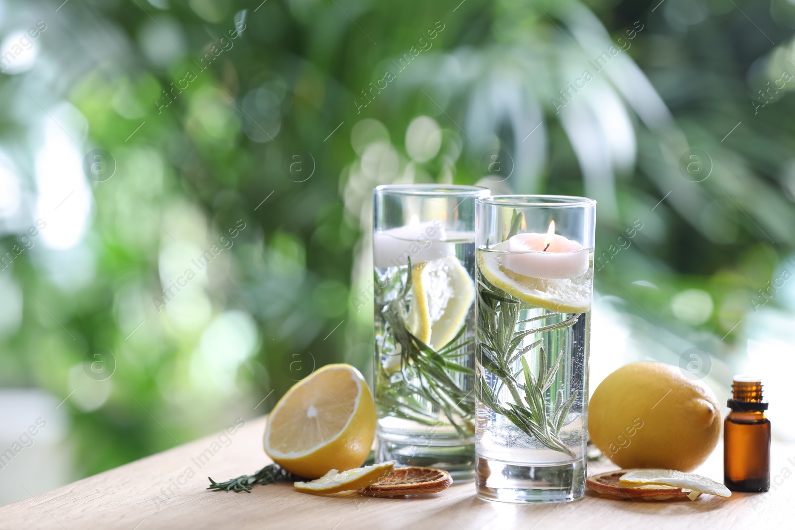 Photo of Natural homemade mosquito repellent candles and ingredients on wooden table outdoors