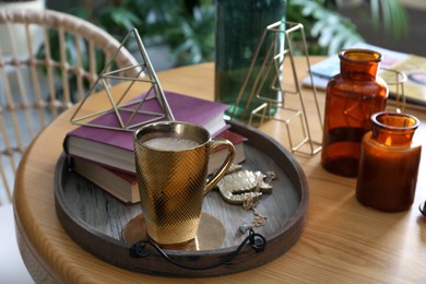 Photo of Wooden tray with decorations, books and hot drink on table indoors