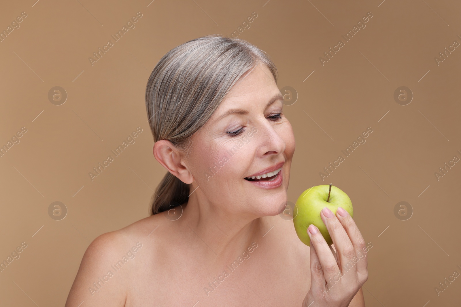 Photo of Beautiful woman with fresh apple on beige background. Vitamin rich food