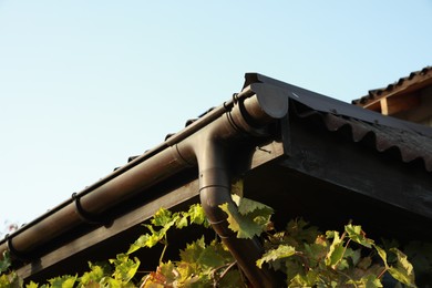 Photo of Rain gutter system with drainpipe on house outdoors, low angle view