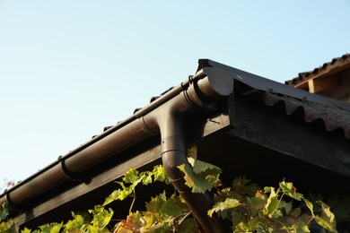 Rain gutter system with drainpipe on house outdoors, low angle view