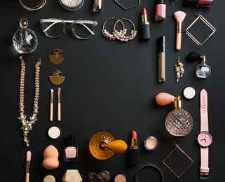 Photo of Frame made of perfume bottles, cosmetics and accessories on black background, flat lay. Space for text