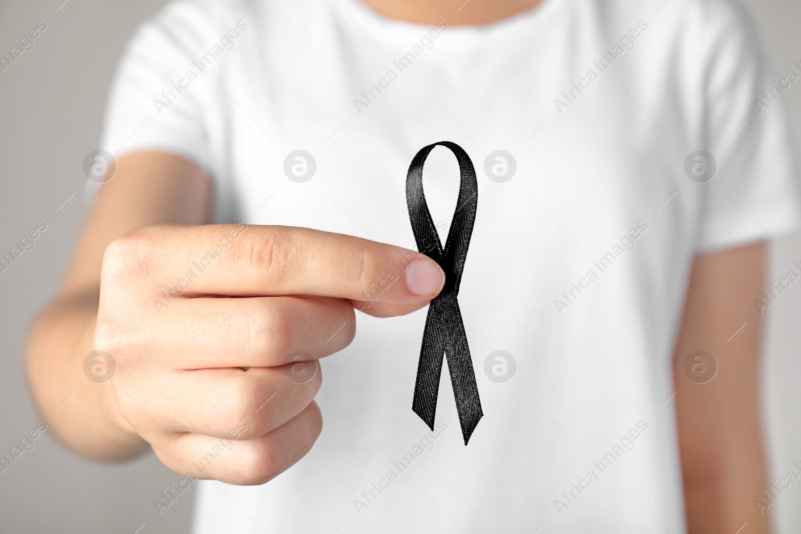 Photo of Young woman holding black ribbon, closeup. Funeral symbol