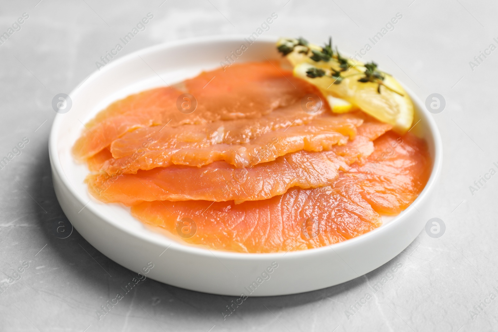 Photo of Plate with fresh sliced salmon fillet and lemon on table