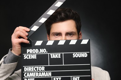 Photo of Adult actor holding clapperboard on black background