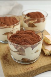 Delicious tiramisu in glasses and cookies on table