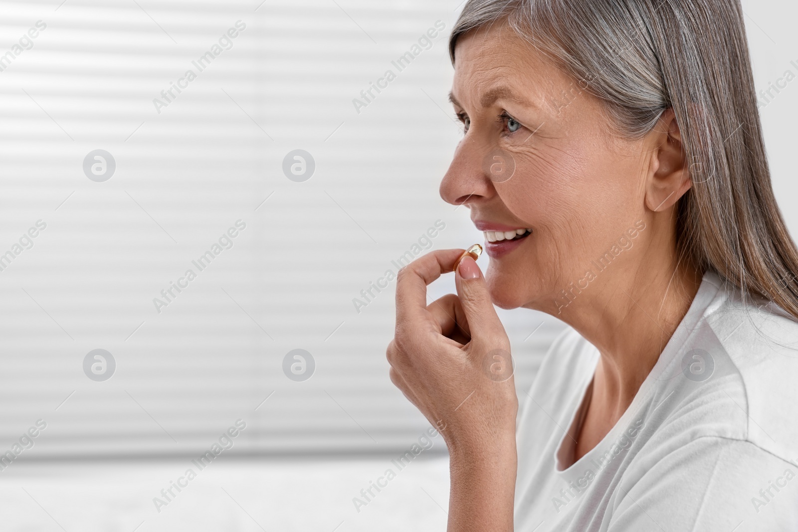 Photo of Beautiful woman taking vitamin pill at home. Space for text