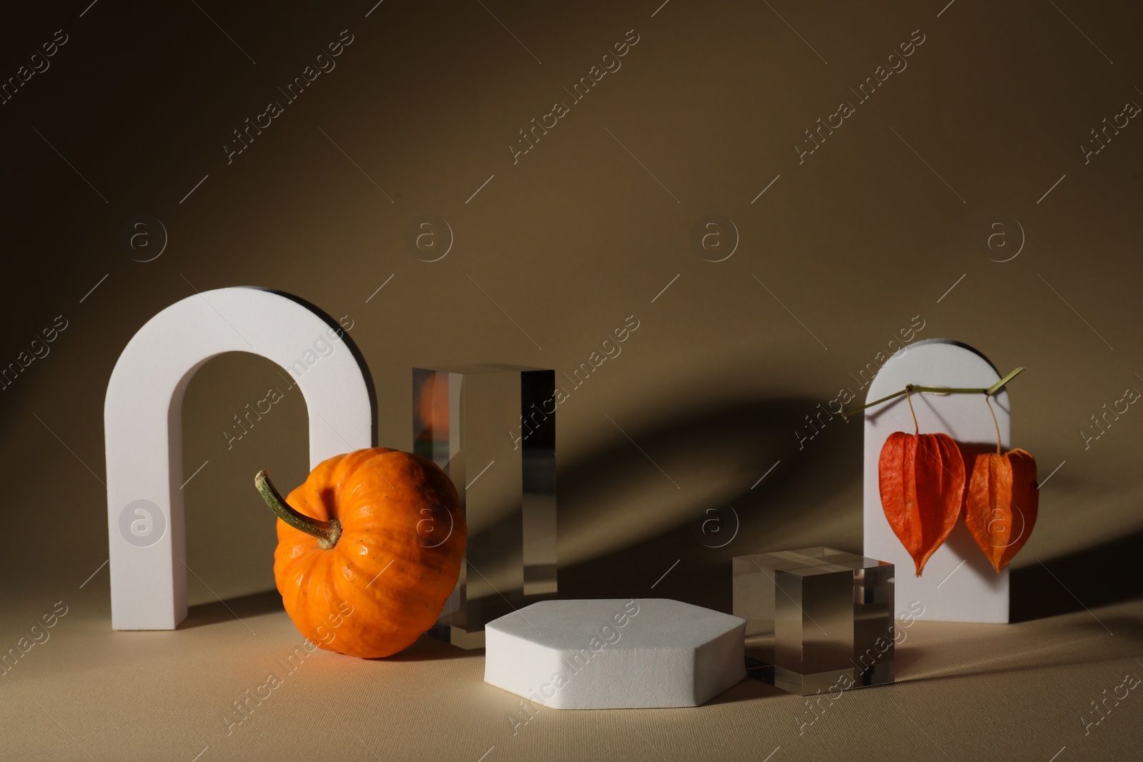 Photo of Stylish presentation for product. Autumn composition with decorative pumpkin and geometric figures on brown background