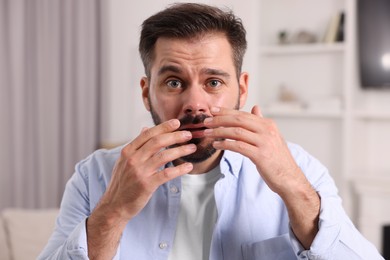 Photo of Skin problem. Confused man touching his face at home