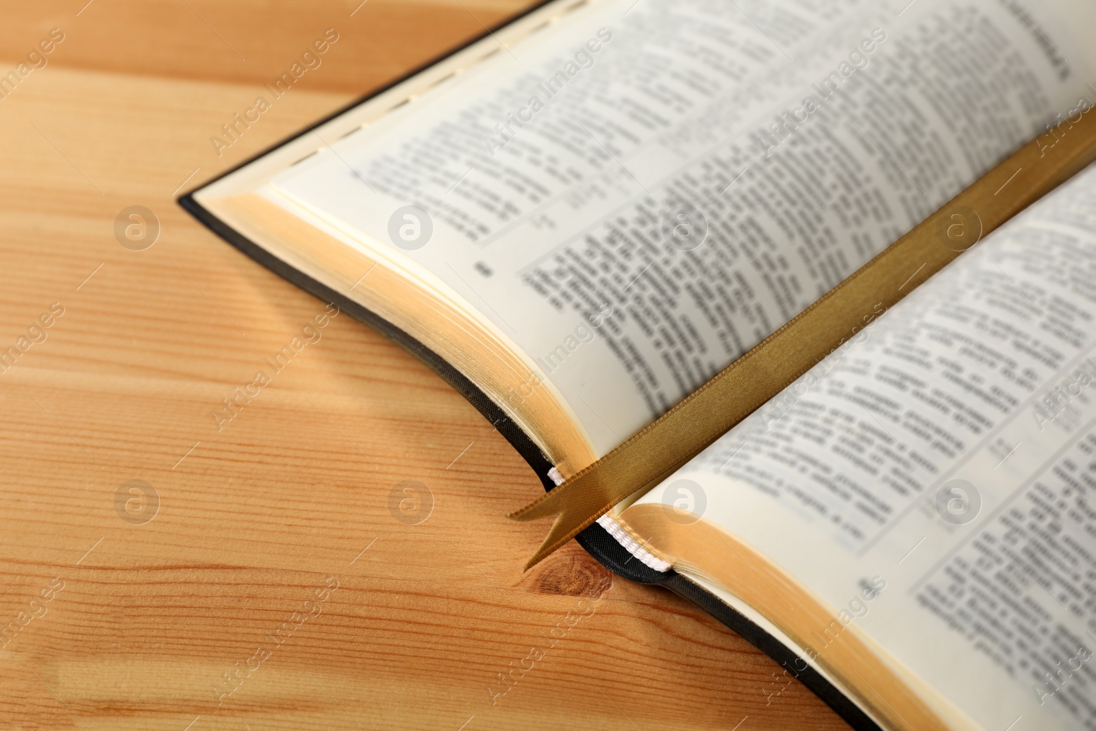 Photo of Open Bible with bookmark on wooden table, closeup