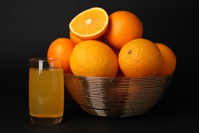 Bowl with ripe oranges and fresh juice on black background