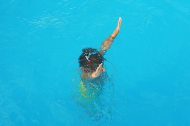 Little child sinking in outdoor swimming pool. Dangerous situation