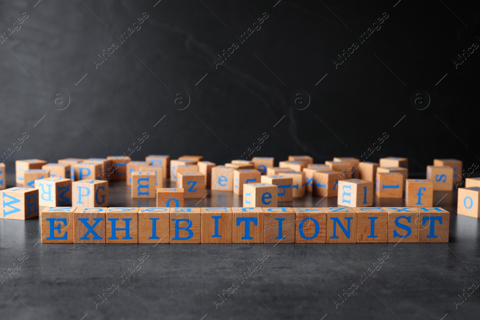 Photo of Word EXHIBITIONIST made with wooden cubes on grey table