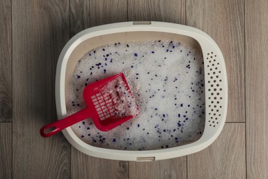 Photo of Cat tray with crystal litter and scoop on wooden floor, top view