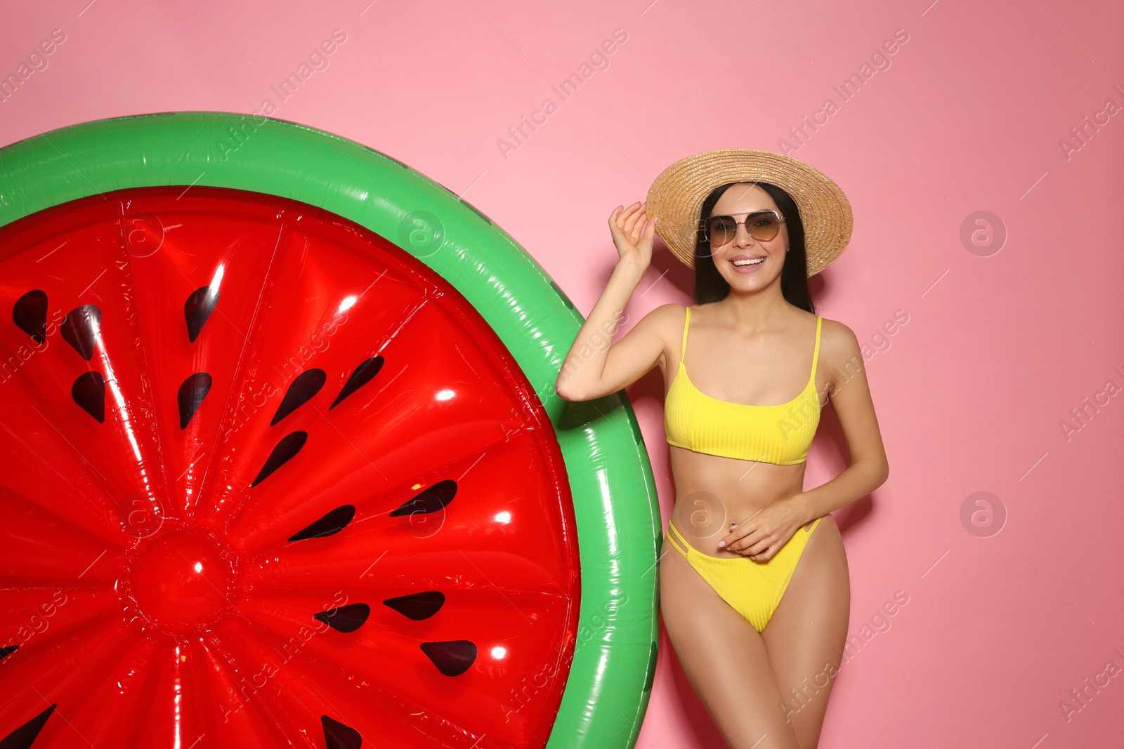 Photo of Young woman with stylish sunglasses near inflatable mattress against pink background