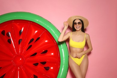 Young woman with stylish sunglasses near inflatable mattress against pink background