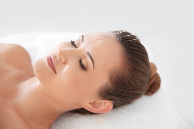 Young woman undergoing acupuncture treatment in salon