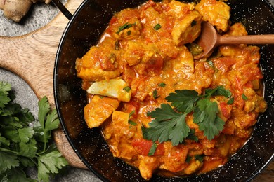 Delicious chicken curry and parsley on grey table, top view