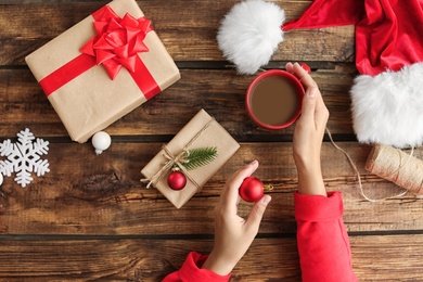 Woman with Christmas gift boxes at wooden table, top view