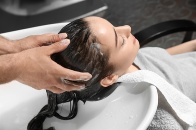 Photo of Stylist washing client's hair at sink in beauty salon