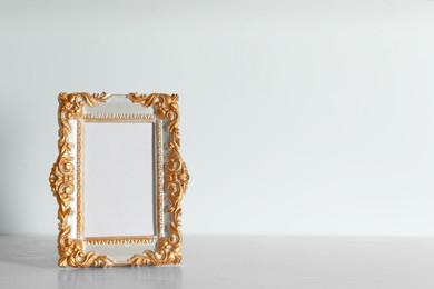 Photo of Beautiful golden vintage frame on white wooden table, space for text