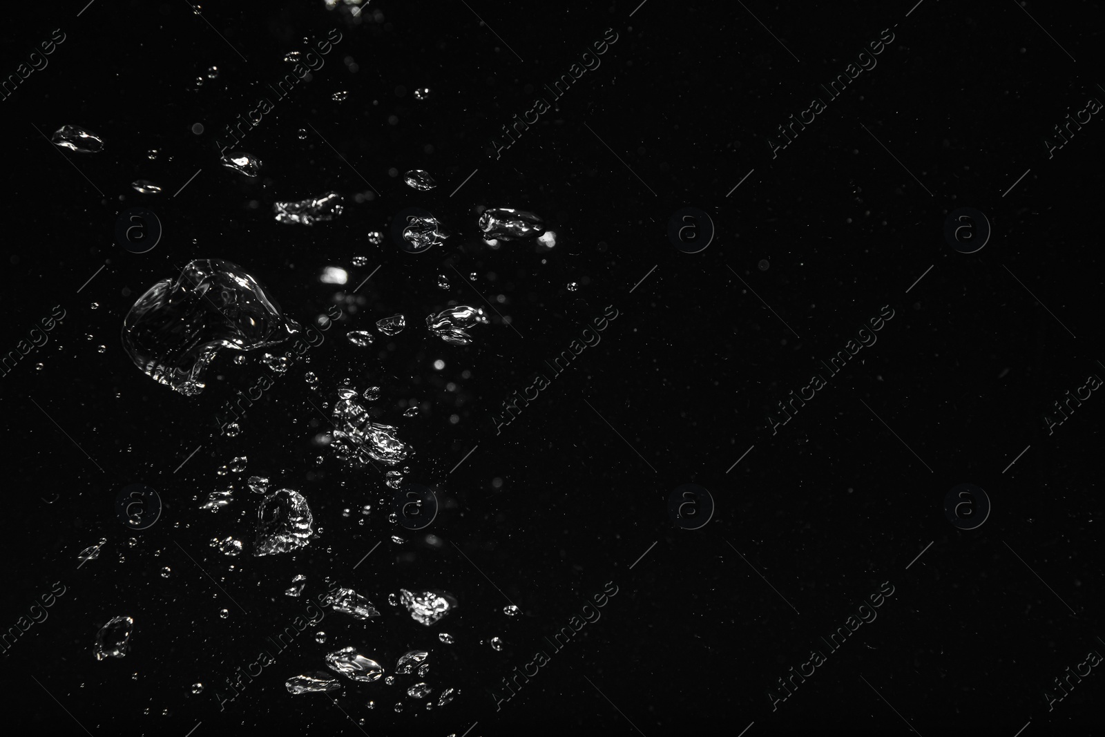 Photo of Air bubbles in water on black background, space for text