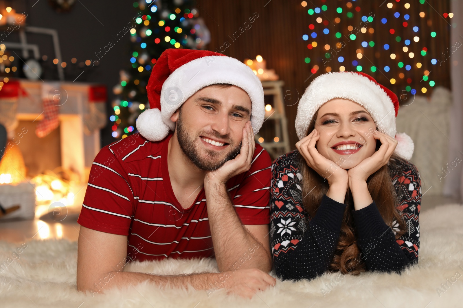 Photo of Happy young couple in Santa hats celebrating Christmas at home