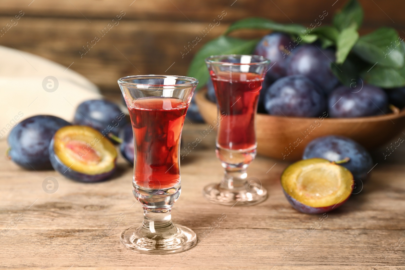 Photo of Delicious plum liquor and ripe fruits on wooden table. Homemade strong alcoholic beverage