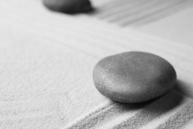 Zen garden stone on sand with pattern, space for text. Meditation and harmony