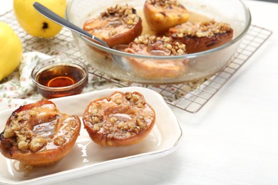 Photo of Delicious quinces baked with honey and walnuts on white table