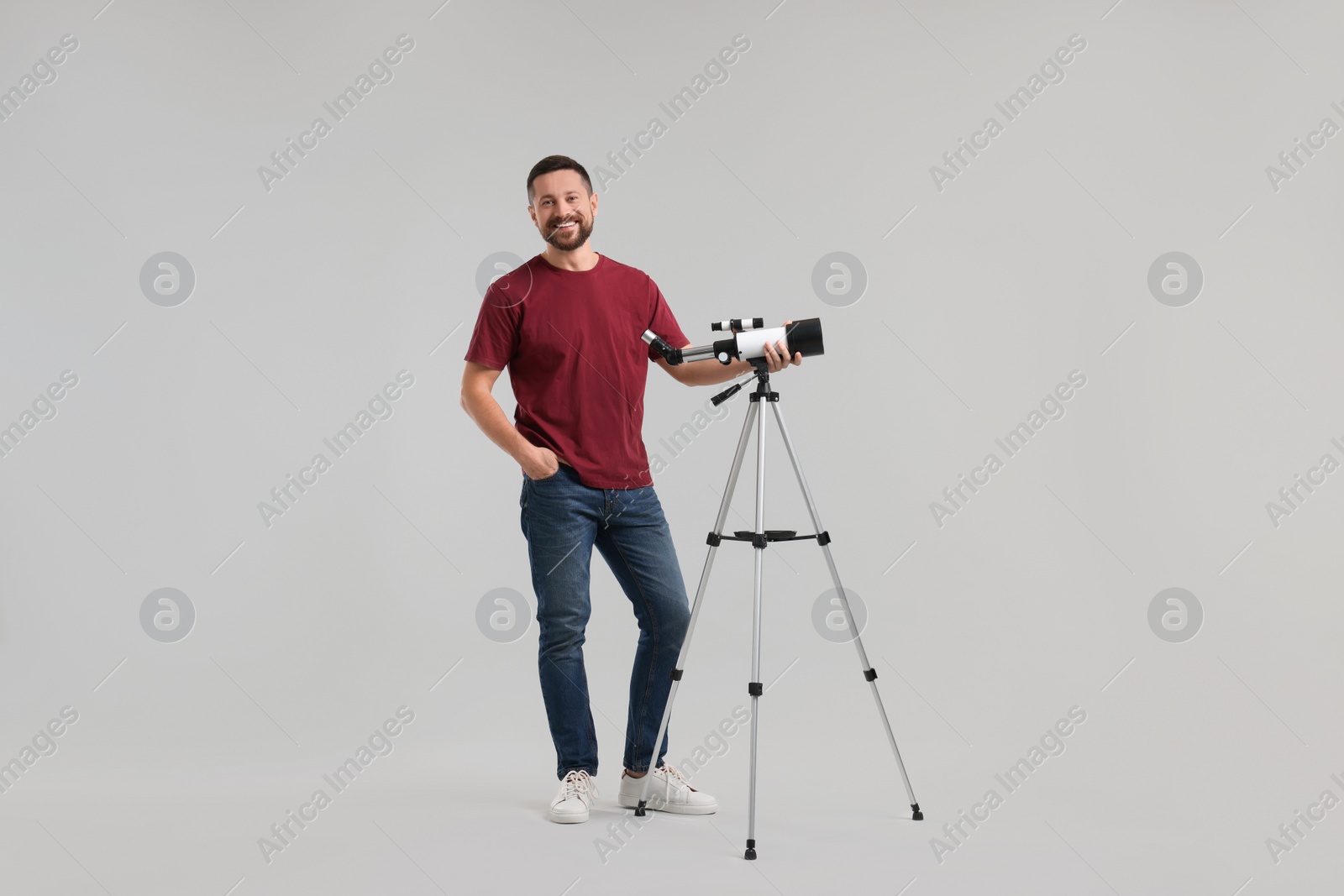Photo of Happy astronomer with telescope on light grey background