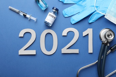 Photo of Flat lay composition with coronavirus vaccine and number 2021 on blue background