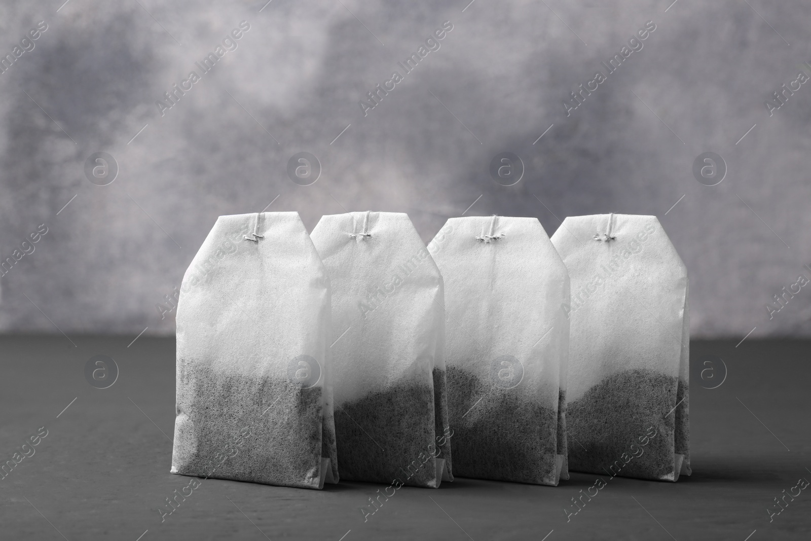 Photo of Many tea bags on grey wooden table, closeup