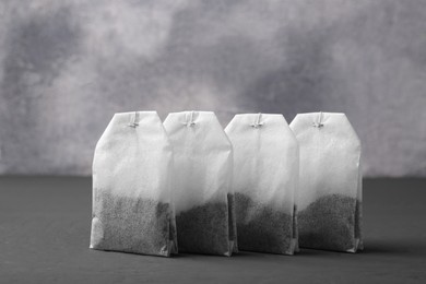 Many tea bags on grey wooden table, closeup