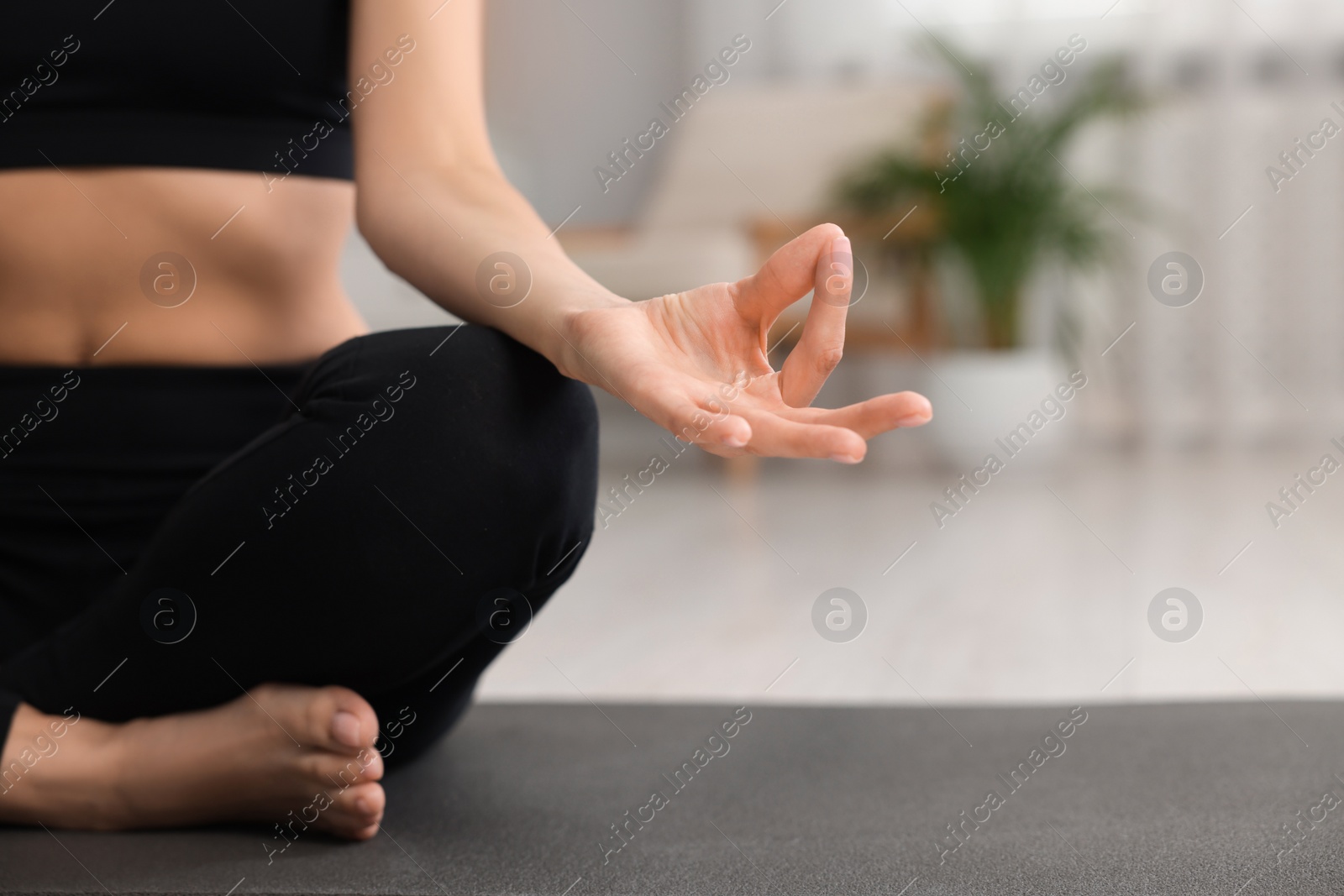 Photo of Woman practicing Padmasana on yoga mat at home, closeup and space for text. Lotus pose