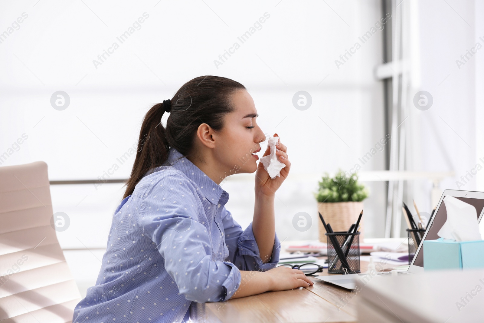 Photo of Sick young woman with napkin in office