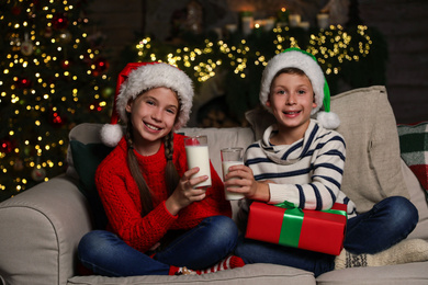 Photo of Happy children with glasses of milk at home. Christmas time