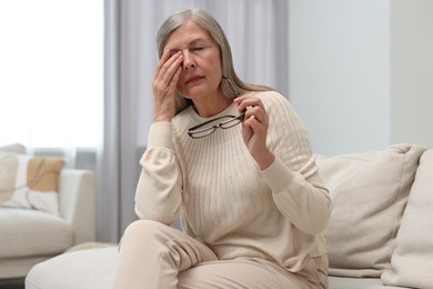 Photo of Overwhelmed woman with glasses sitting on sofa at home