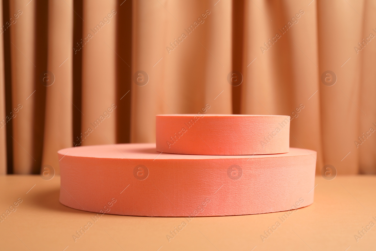 Photo of Geometric figures on table against light brown curtain. Stylish presentation for product