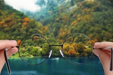 Vision correction. Woman looking through glasses and seeing landscape clearer