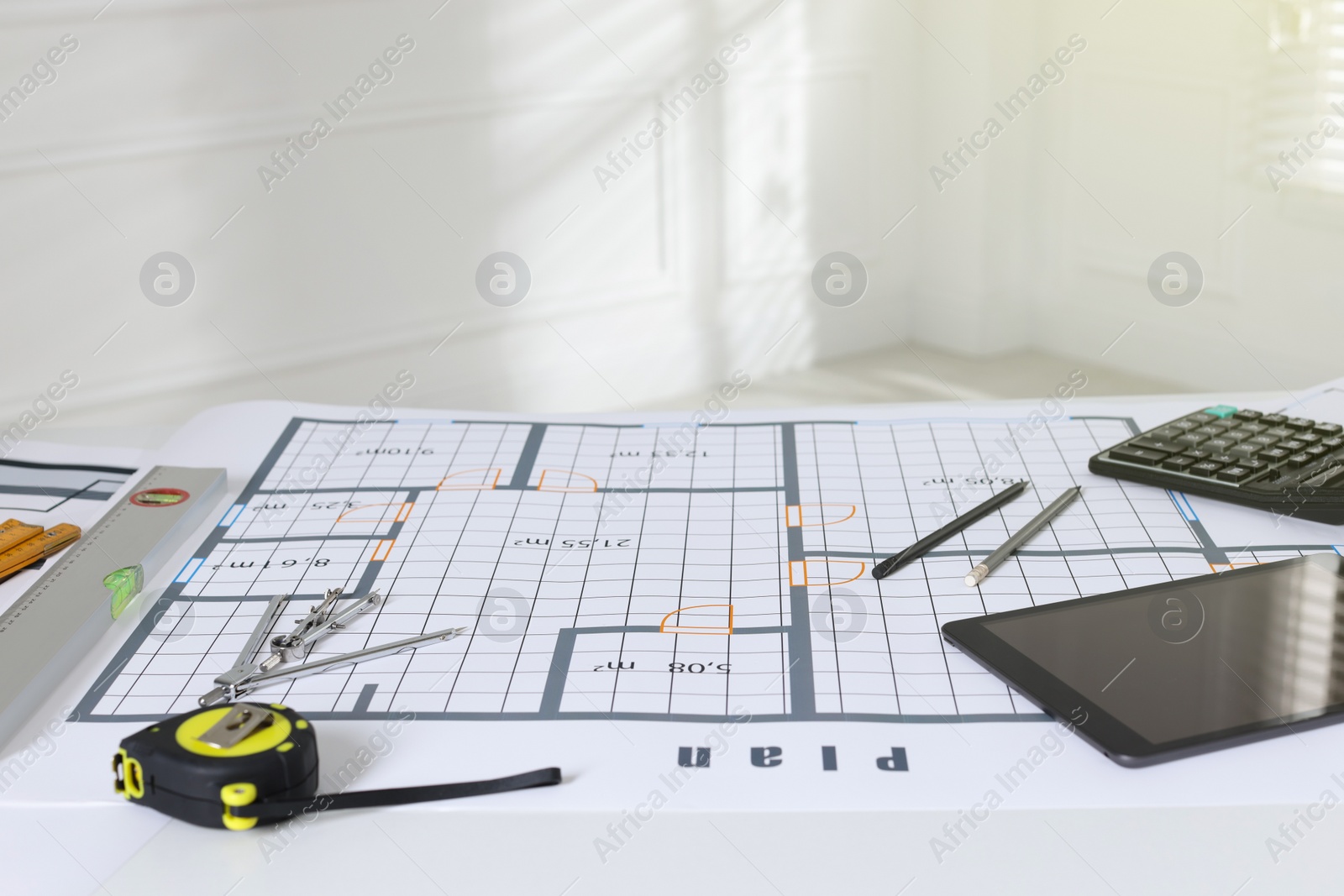 Photo of Construction drawing, tablet and roulette on table in office