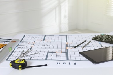 Photo of Construction drawing, tablet and roulette on table in office