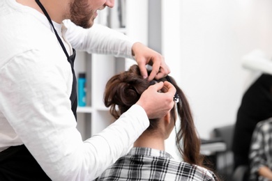 Photo of Professional male hairdresser working with client in salon