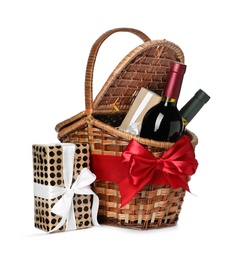 Festive basket with bottles of wine and gifts on white background