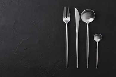 Photo of Beautiful cutlery set on black table, flat lay. Space for text