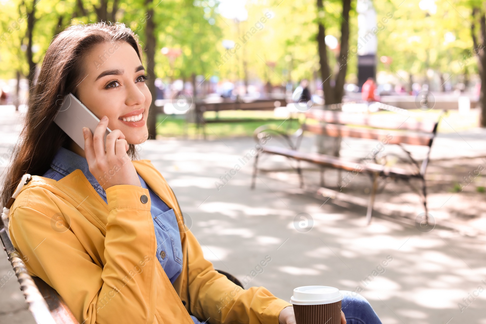 Photo of Young woman talking by phone outdoors on sunny day